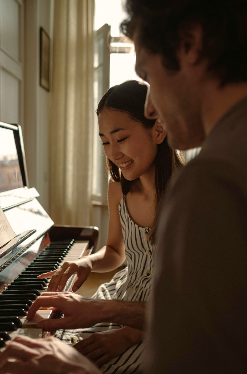 Girl playing the piano with teacher