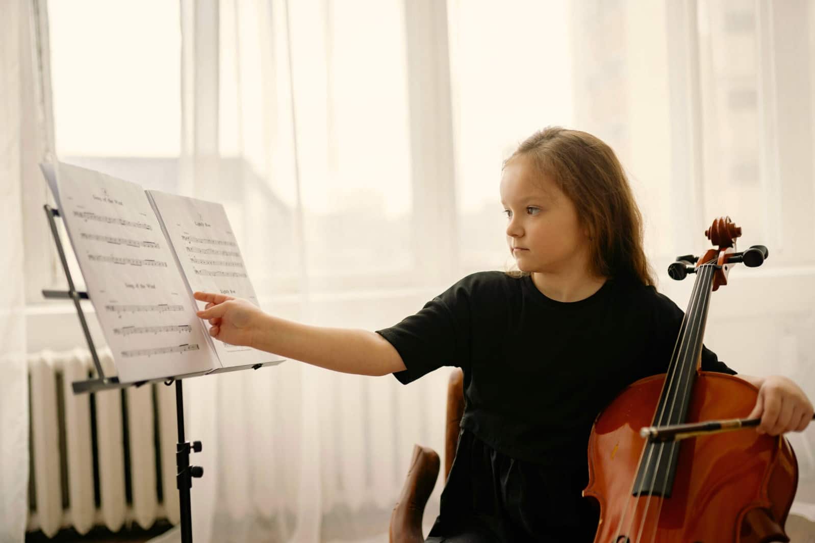 Little girl look at her notes holding a cello during a cello lesson