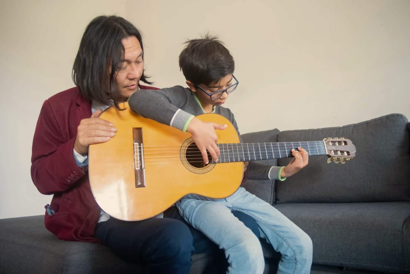 Boy having a guitar lesson next to guitar teacher
