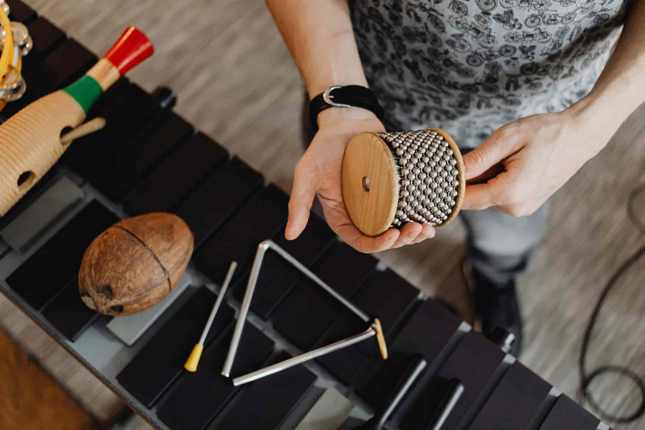 Percussionist holding a cabasa above a triangle.