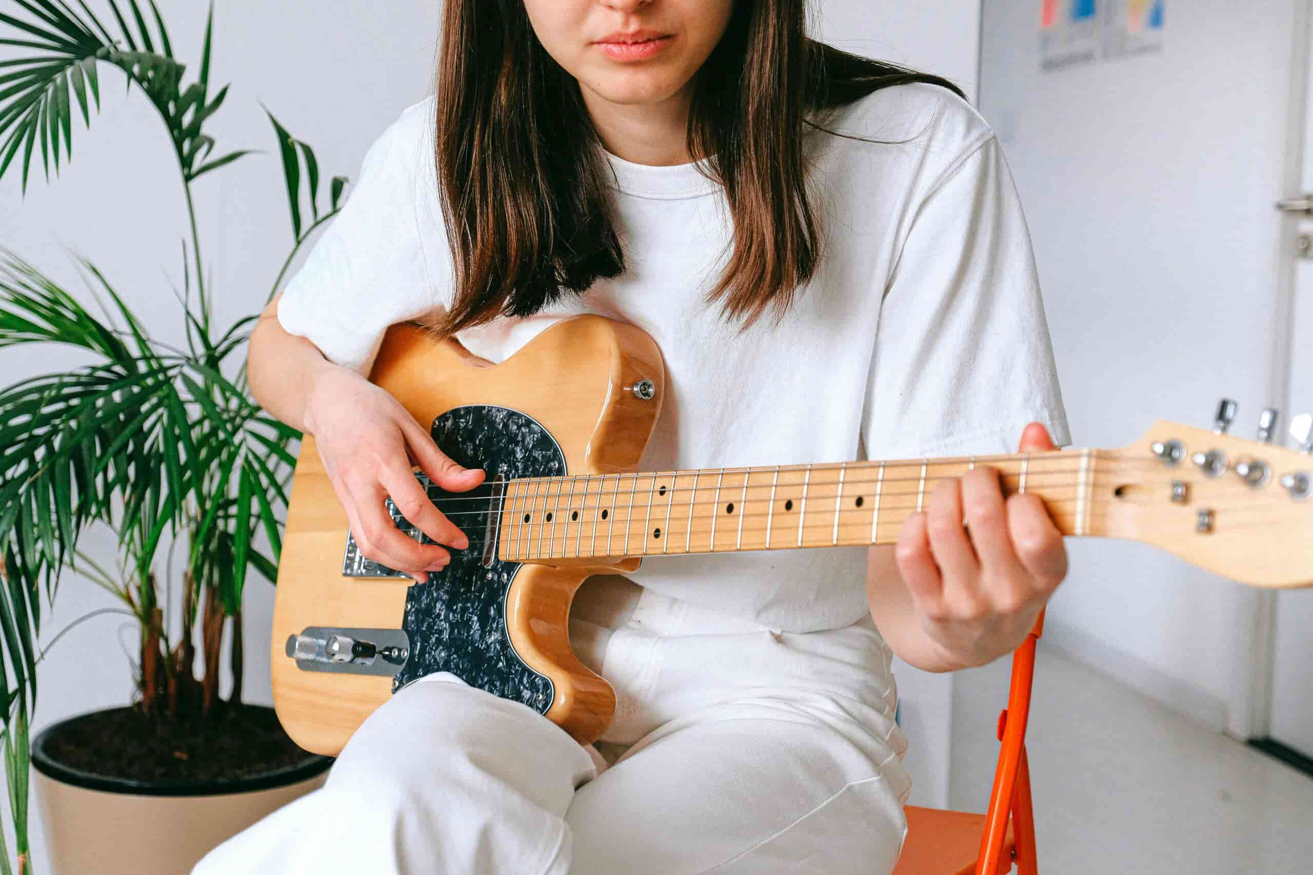 Woman playing electric guitar, with only the bottom half of her face showing.