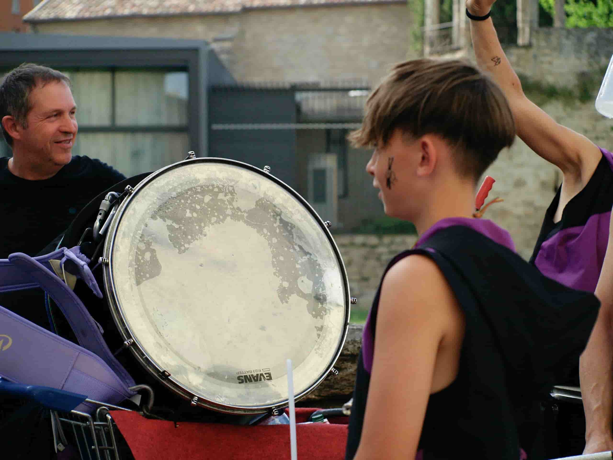 Boy facing a drum on the street and a conductor during drum lessons