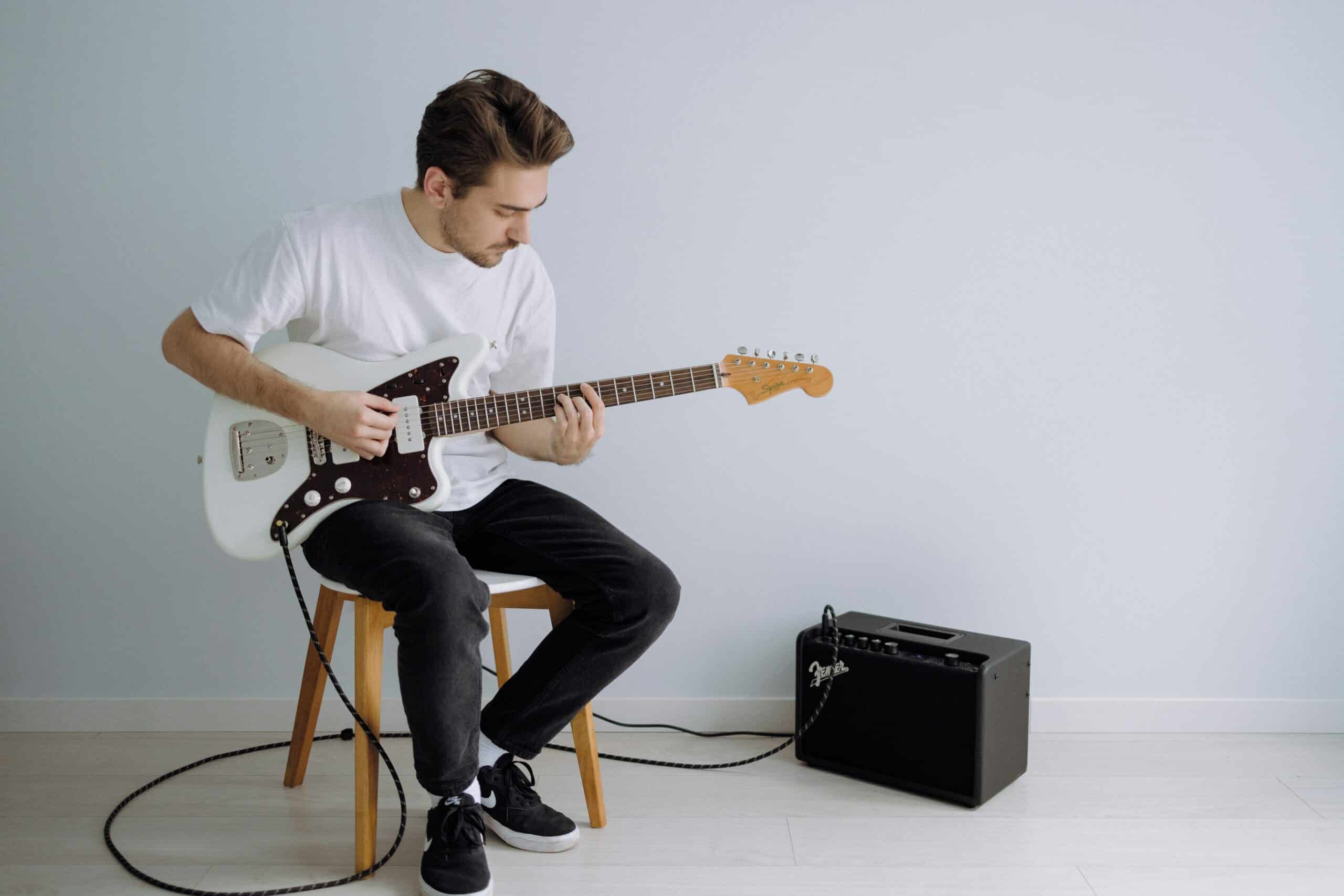 Man playing electric guitar lessons with white backdrop