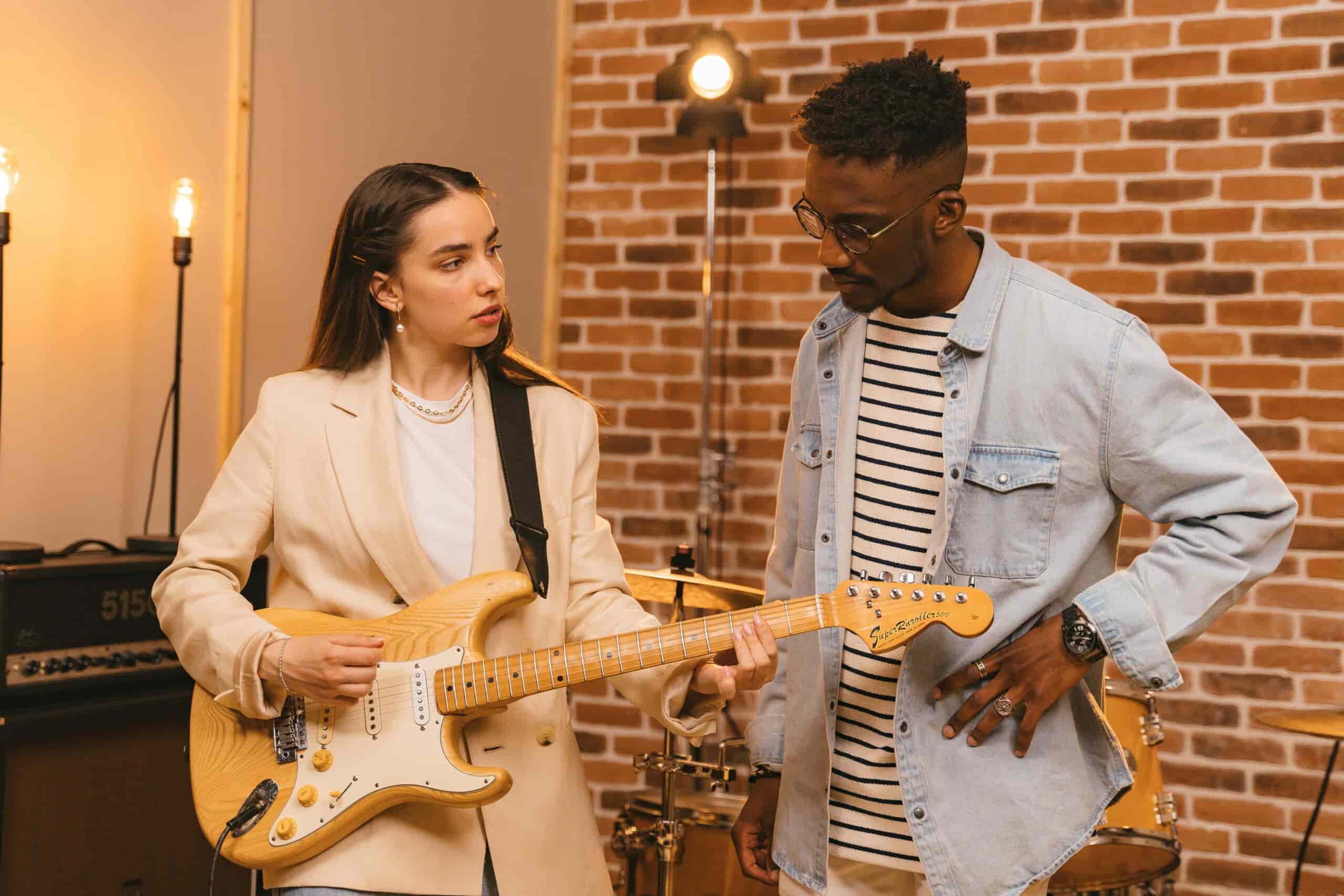 Woman holding an electric guitar next to a man
