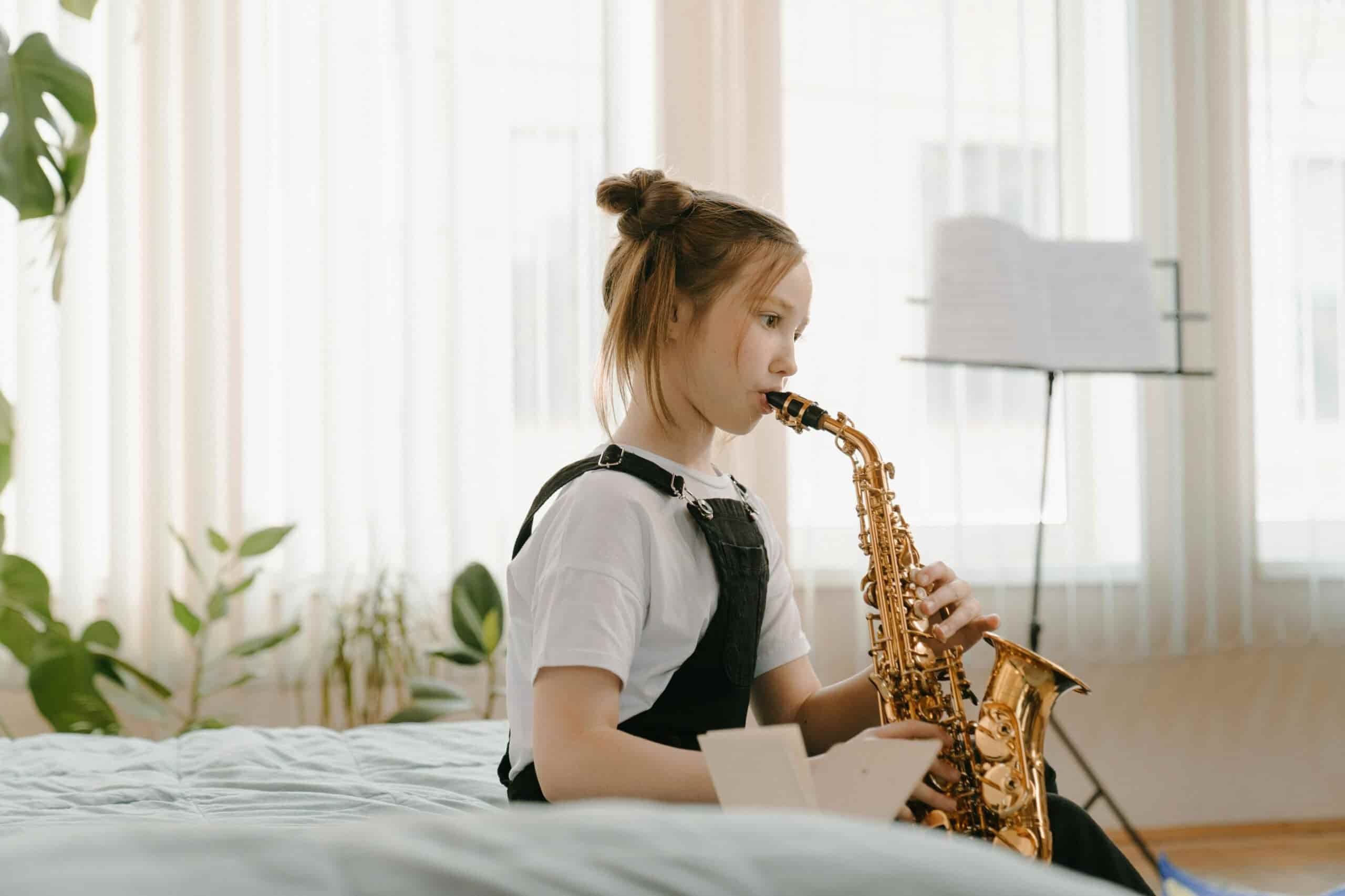 Little girl taking saxophone lessons with note-stand in background.