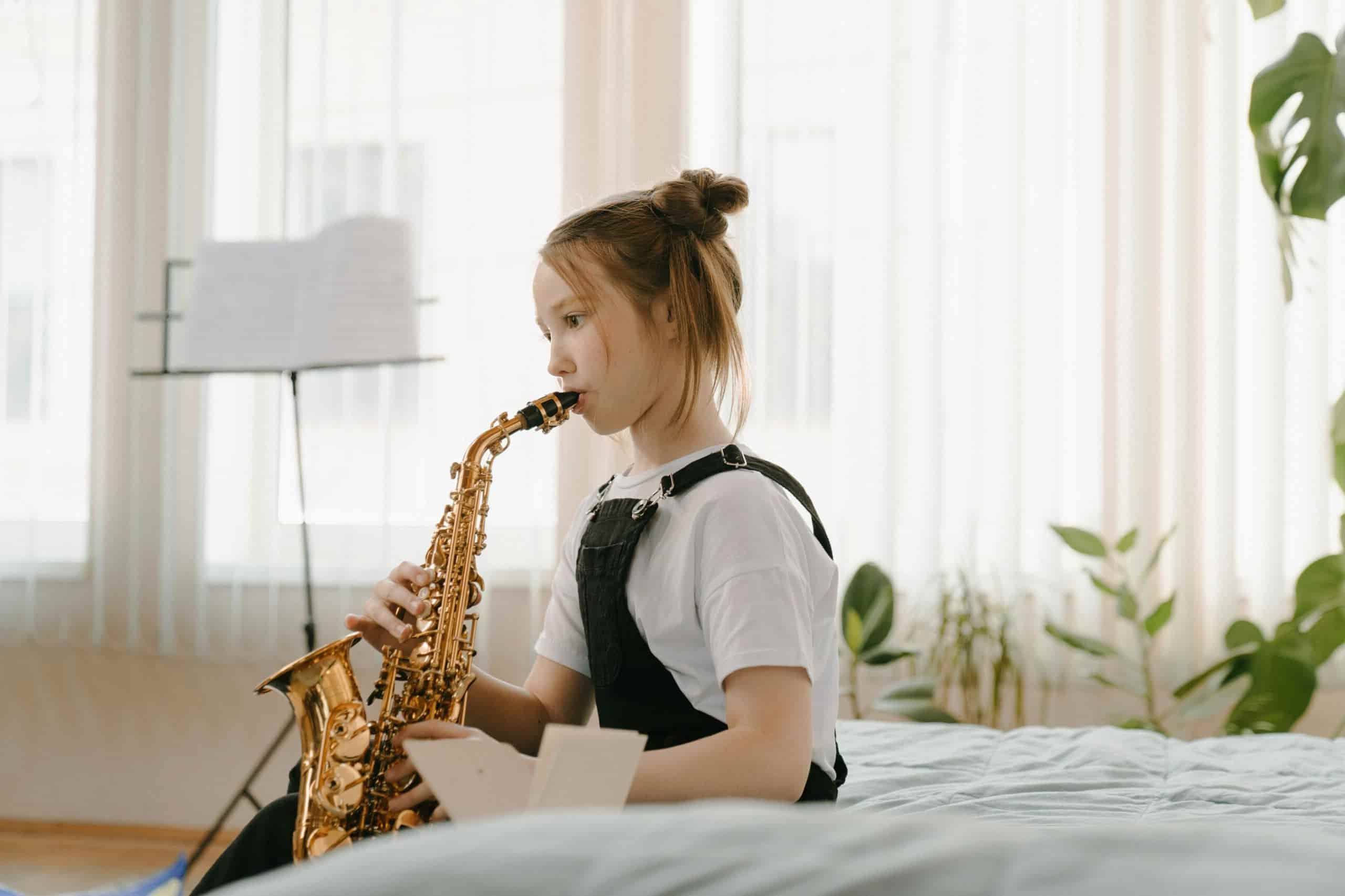 Little girl taking saxophone lessons with note-stand in background.