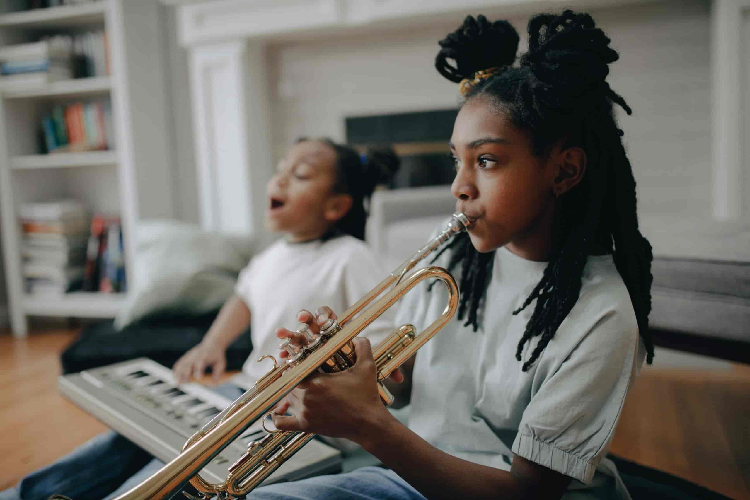 Girl taking trumpet lessons with girl on keyboard in background
