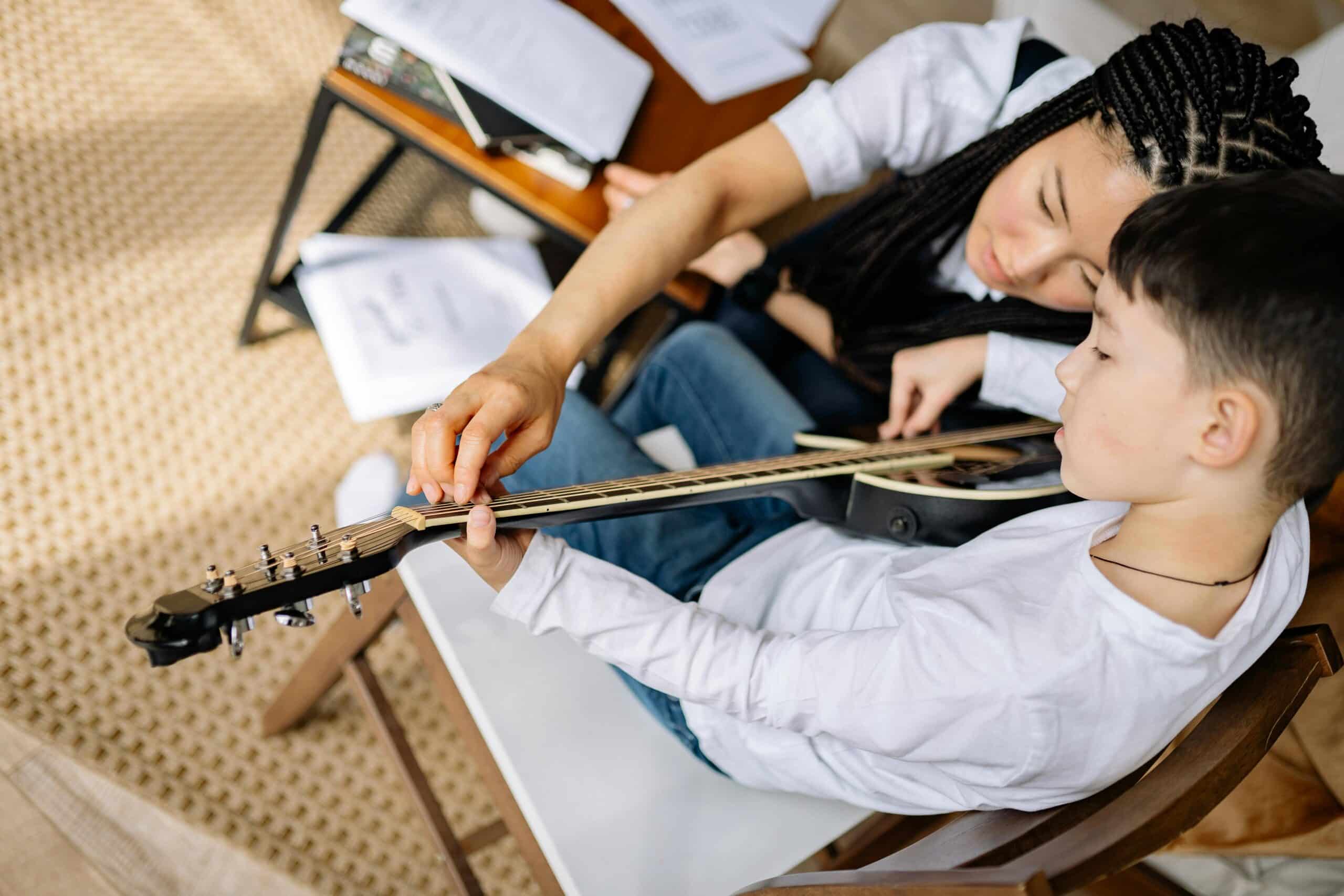 Top view shot of guitar teacher helping child learn guitar
