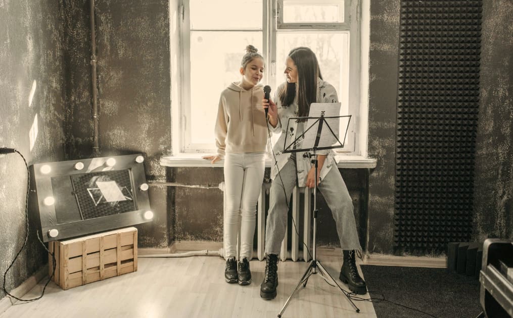 Girl in singing lessons with singing teacher