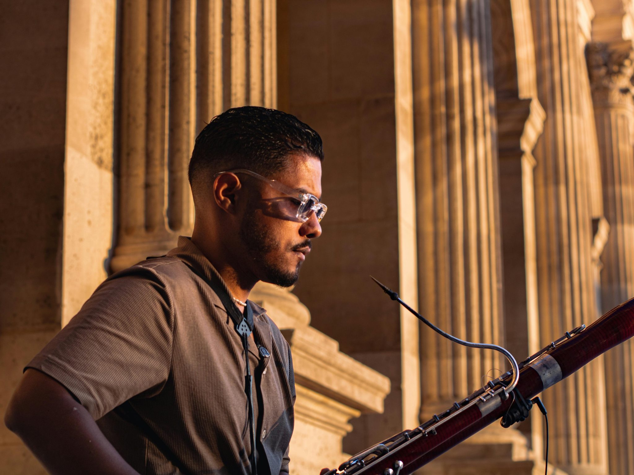 Man playing the bassoon outside in front of old building