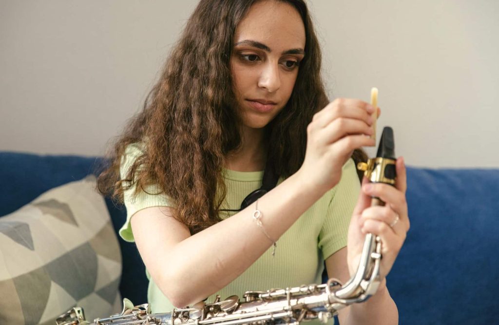 Girl putting reed on saxophone during lesson