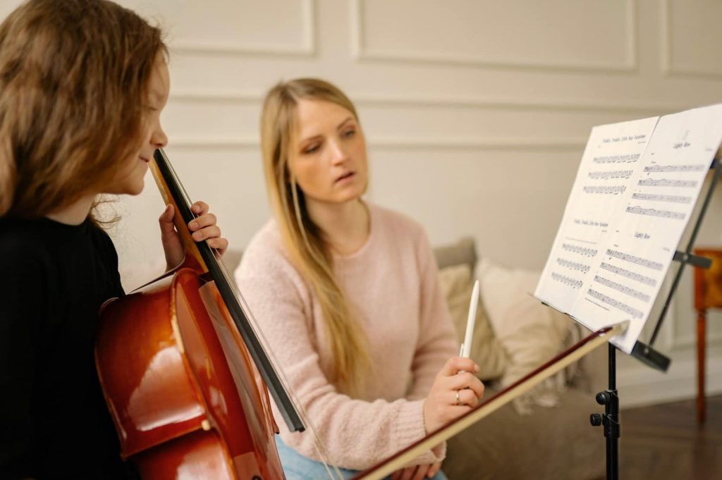 Cello teacher showing cello student sheet music during cello lessons
