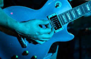 A blue lighting shot of a sparkly blue electric guitar