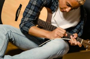 Boy songwriting with his guitar in songwriting lessons