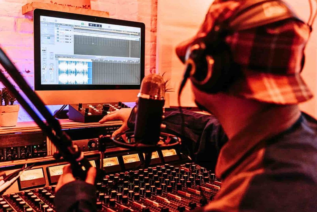 man in studio working on music production software with headphones and a mic