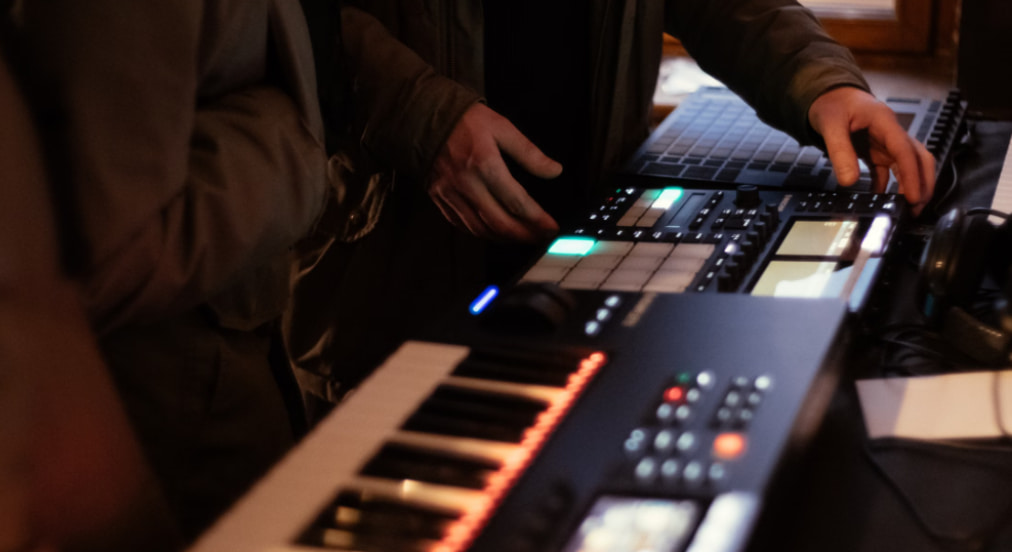 A music producer using a MIDI keyboard and drum pad controller to start learning music production