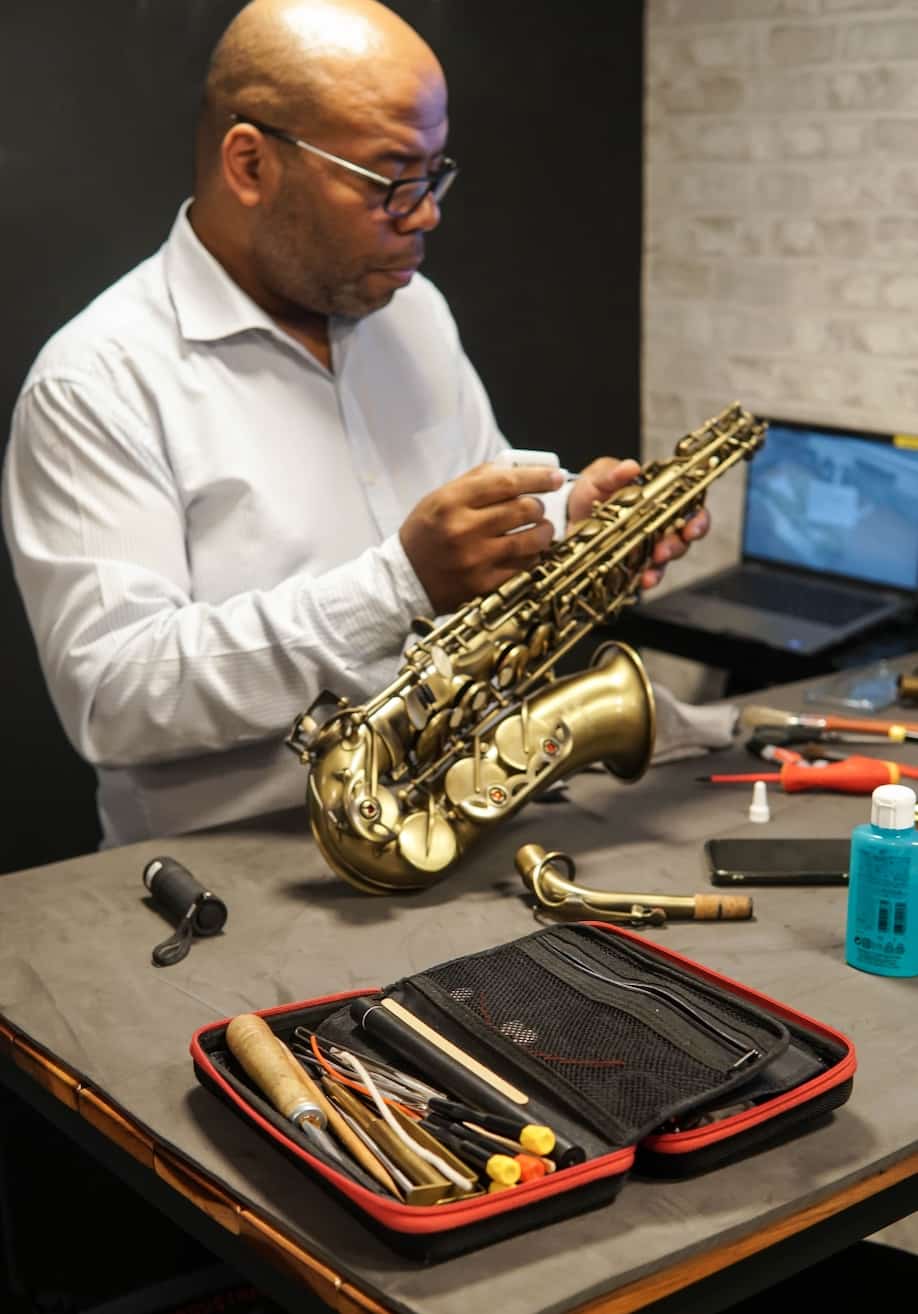 man fixing saxophone