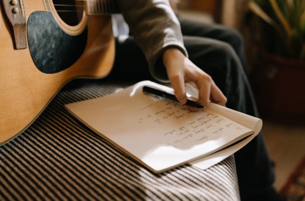 A person writing a song with guitar