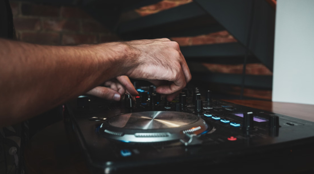 Hands adjusting equipment during a DJ lesson